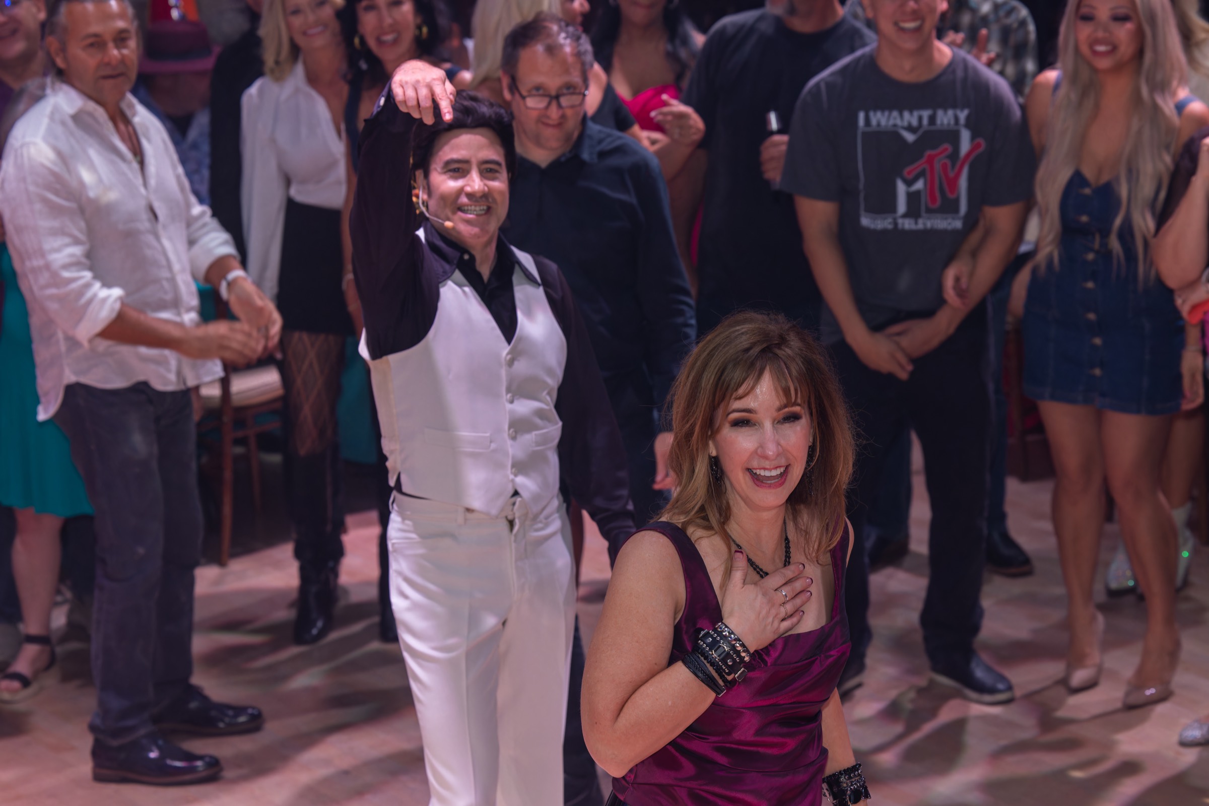 Travolta-style performer dancing with a guest while a crowd watches